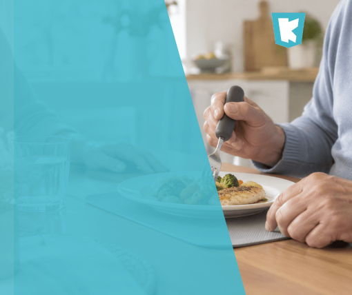 Persona mayor comiendo con un tenedor de mango engrosado en la mesa de su casa
